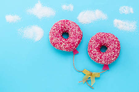 Creative food minimalism. Donut on blue background, donut in a shape of balloon in the sky, top...