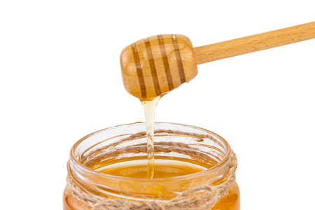 Honey pot and dipper isolated on white background.の写真素材