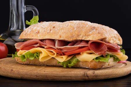 Ciabatta sandwich with lettuce , prosciutto and  cheese on wooden board.の写真素材