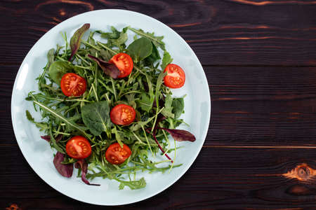 Arugula salad and tomatoes on a wooden background. View from aboveの写真素材