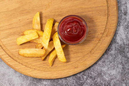 French fries with ketchup on wooden background, top view.