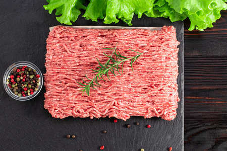 raw minced meat and spices on dark background., top view.