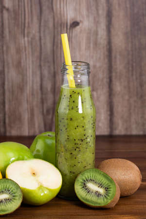 Blended green smoothie with kiwi and green apple on wooden background.の写真素材