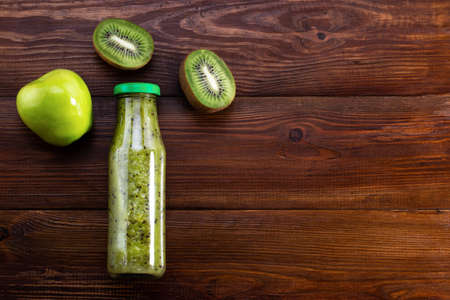 Blended green smoothie with kiwi and green apple on woodenの写真素材
