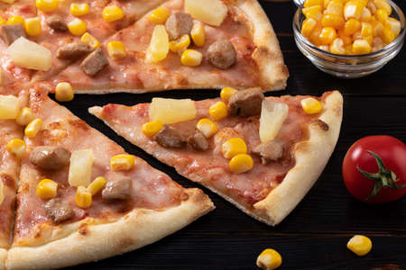 Pizza with chicken, pineapple and corn isolated on wood background.の写真素材