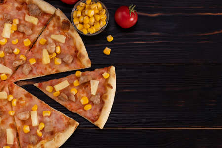 Pizza with chicken, pineapple and corn isolated on wood background with copy space.の写真素材