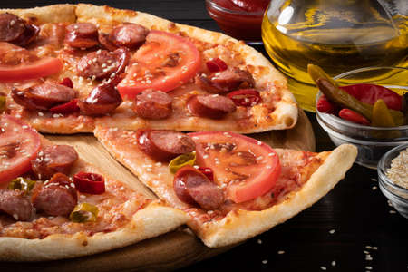 pizza with bavarian sausages, tomato and chili pepper on dark background.の写真素材
