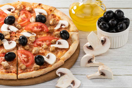 Pizza with chicken, mushrooms and olives on wooden background.の写真素材