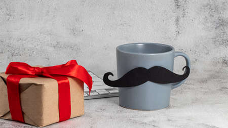 Happy fathers day concept. coffee cup with black paper mustachewith a gift and glasses on table background. Ð¡opy space.の写真素材