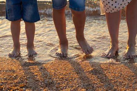feet of mom and children stand on the beach by the sea.の写真素材