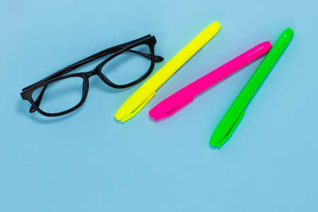 Education concept. Glasses and three markers on a blue background with copy space.の写真素材