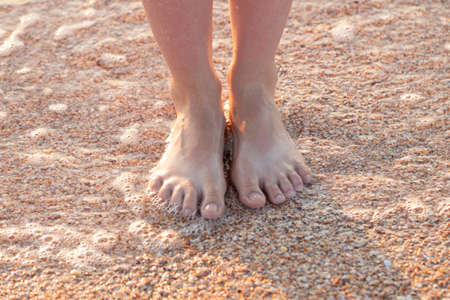 girl barefoot on the beach in summer. Feet in the water.