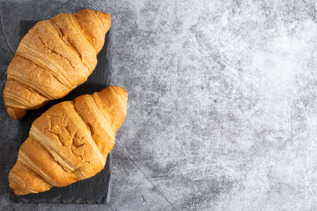 fresh croissants and coffee on stone background with copy space. Top view.