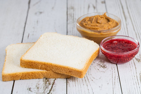 bread, jam and peanut butter on a light background.