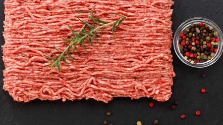 raw minced meat and spices on dark background., top view.