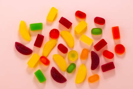 colored jelly sweets and marmalade on a pink background top view.