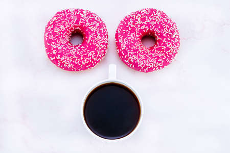 donuts like eyes and a cup of coffee. Top view. Minimalist concept morning.