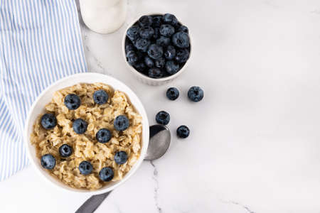 Oatmeal with blueberries and milk on a light background. Breakfast top view with copy space.の写真素材