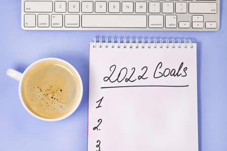 goals 2022 with keyboard and coffee cup on purple background. New Year resolutions and goal setting concept.の写真素材