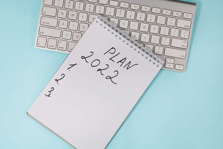 Business concept of 2022 goals list with notebook and keyboard on a blue background, top view.の写真素材