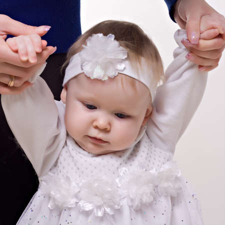 little girl on a white background learning walking with his mother