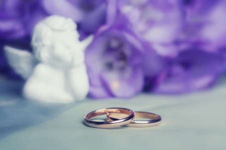 Wedding ring against flowers and small angel figureの写真素材