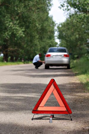 The image of emergency stop sign under the foreground and man near car under background  Focus is under the sign の写真素材