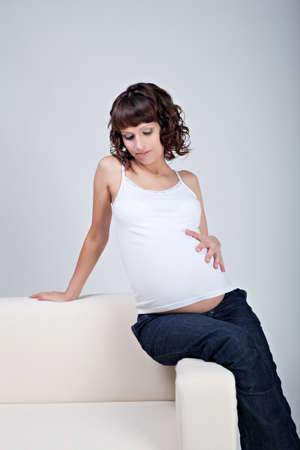 Young pregnant woman sitting on sofaの写真素材