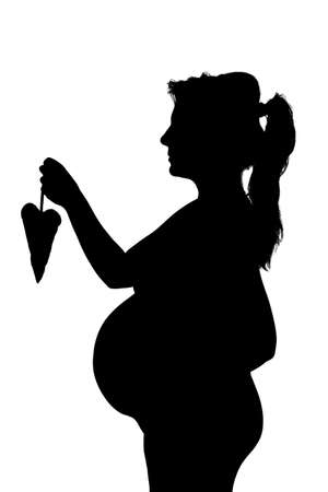 Silhouette of the pregnant woman with heart shape isolated on whiteの写真素材