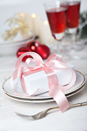 Festive table setting with gift on plateの写真素材