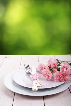 Plate with silverware on wooden table over green bokeh backgroundの写真素材