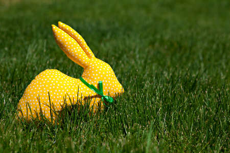 Yellow textile rabbit on green grass