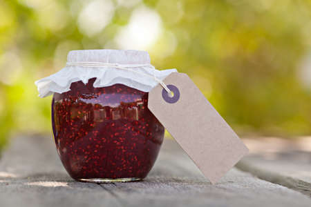 Raspberry jam in a jar and fresh berries on the wooden tableの写真素材