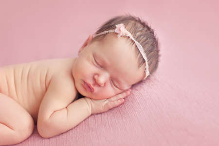 Newborn baby girl posing on pink backgroundの写真素材