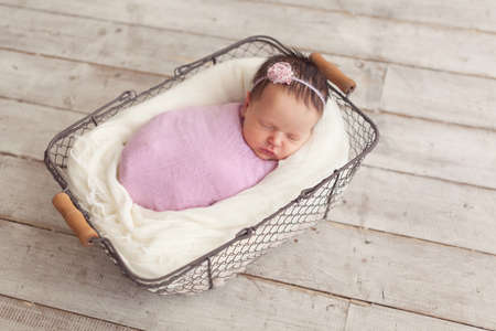 Newborn baby girl posing in basketの写真素材
