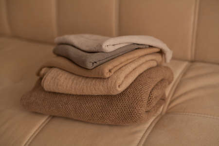 A stack of different fabrics of beige shades on the couch