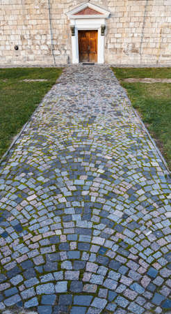 Road cobbled by a granite stone blocks overgrown with mossの写真素材