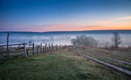 Country road leading to the foggy pondの写真素材