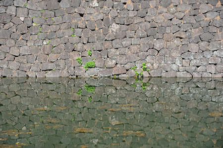 Stone wall and its reflection on the surface of the water.の写真素材