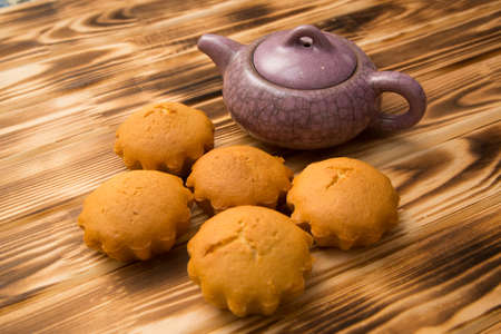 Cupcakes and a teapot on a brown Boardの写真素材