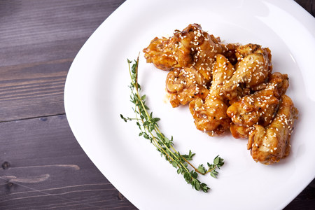 Pieces of chicken on a white plate sprinkled with sesame seeds