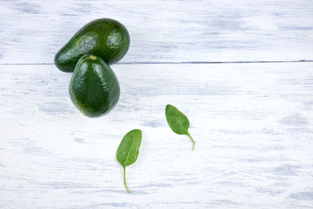 Avocado on white wooden background with green leavesの写真素材