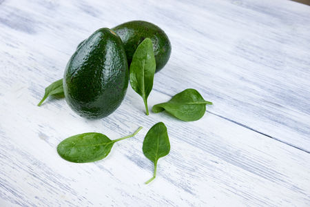 Avocado on white wooden background with green leavesの写真素材