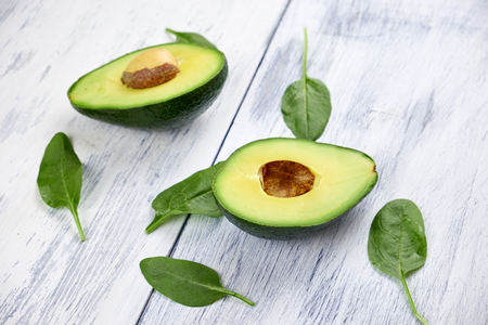 Slices of avocado on white background. Whole and half with leaves.の写真素材