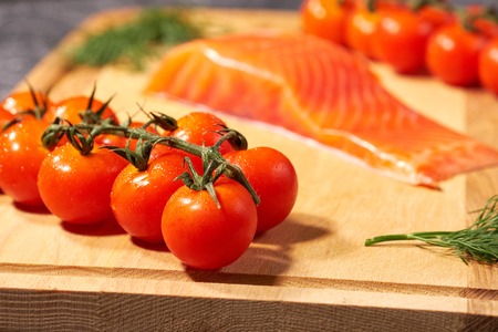 A piece of salmon on a wooden Board, tomatoes and dill. Selective focusの写真素材