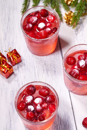 Glasses with cranberry juice on white wooden background with pine branch in the backgroundの写真素材