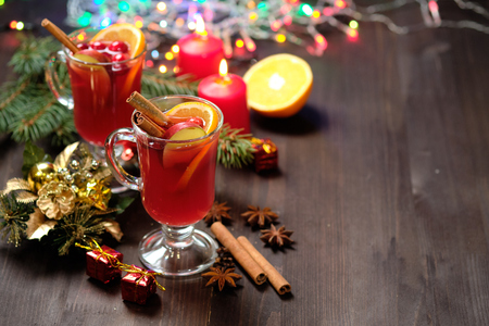 Mulled wine on a wooden background with candles, pine branches and Christmas lightsの写真素材