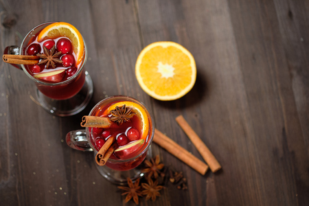 Mulled wine on a wooden background with candles, pine branches and Christmas lightsの写真素材
