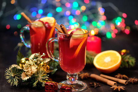 Mulled wine on a wooden background with candles, pine branches and Christmas lights.の写真素材