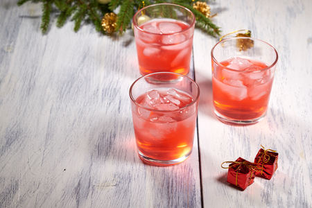 Glasses with cranberry juice on white wooden background with pine branch in the backgroundの写真素材